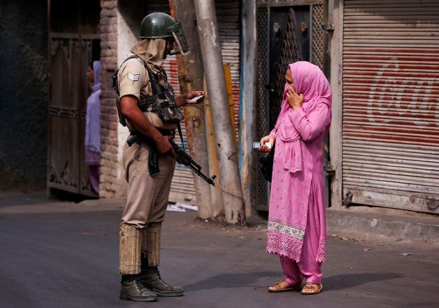 An Indian policeman checks an identity card of a woman during a curfew in Srinagar.