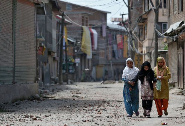 Two women and a girl make their way along a street littered with rocks thrown by protestors in Srinagar as the city remains under curfew following weeks of violence in Kashmir.