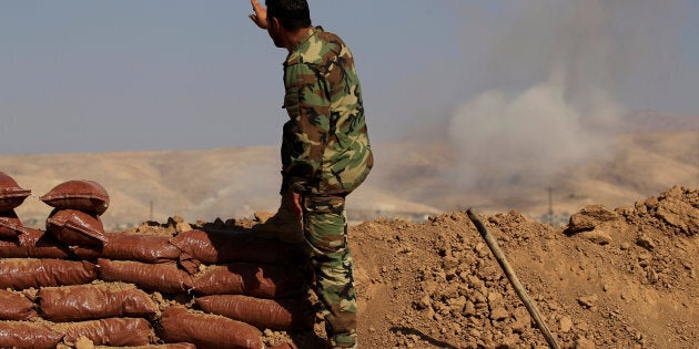 A Kurdish Peshmerga soldier who is stationed between two front lines gestures as a smoke rises near Bashiqa, east of Mosul, Iraq October 29, 2016. REUTERS/Zohra Bensemra