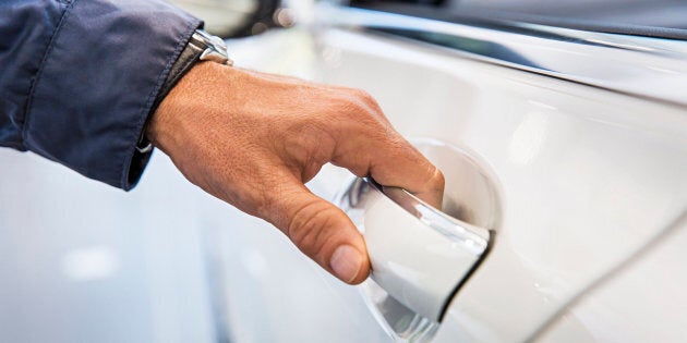 Man's hand on white car door handle