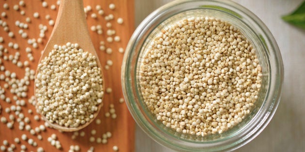 Quinoa is in the glass container and a wooden spoon,Super food