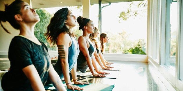 Women practicing yoga in studio in cobra pose