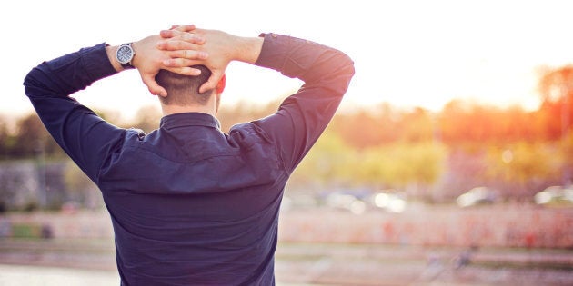 Rear view of young man in shirt holding head in hands