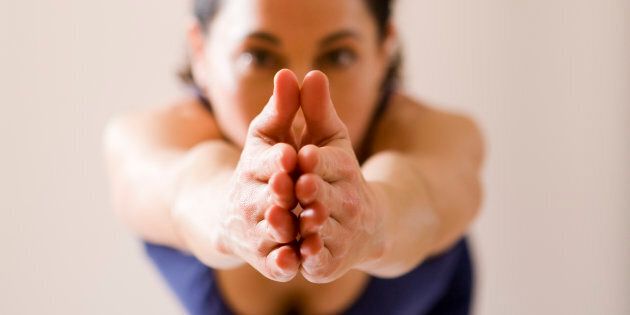 A yoga instructor poses with her hands together.