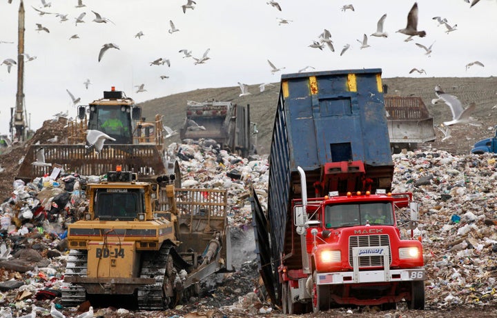 A garbage truck empties its load as bulldozers process the waste at the Central Landfill, in Johnston, Rhode Island, U.S.A.