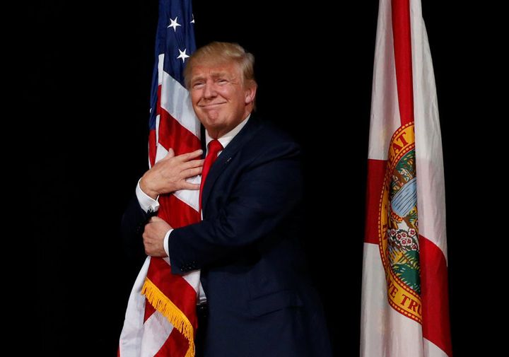 Donald Trump hugs a U.S. flag at a rally in Tampa, Florida