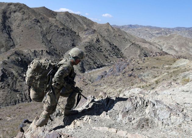 A U.S soldier climbs a hill with a heavy rucksack In Afghanistan in 2012