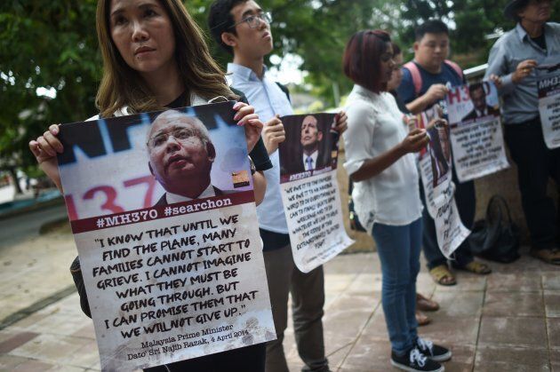 Relatives of passengers missing on Malaysia Airlines MH370 hold placards.