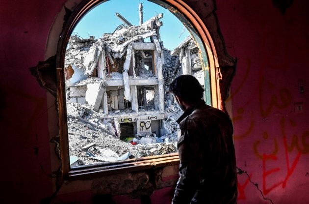 A member of the Syrian Democratic Forces looks out from a building at the frontline in Raqa on October 16, 2017.