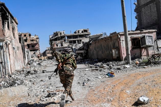 A member of the Syrian Democratic Forces (SDF) runs as he tries to take a cover near Raqa's stadium as they clear the last positions on the frontline.