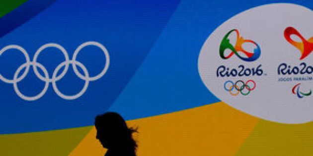 A journalist walks in front of a screen with olympics logos during the medal launching ceremony in Rio de Janeiro, Brazil, June 14, 2016. REUTERS/Sergio Moraes