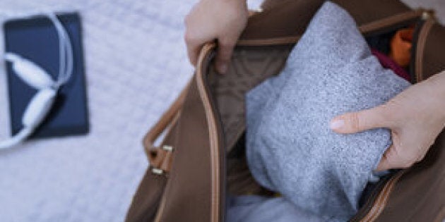 Woman packing travel bag on a bed