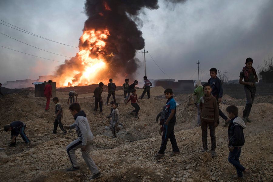 Children play next to a burning oil field in Qayara, south of Mosul on Nov 3. A senior military commander said more than 5,000 civilians have been evacuated from newly-retaken eastern parts the city.