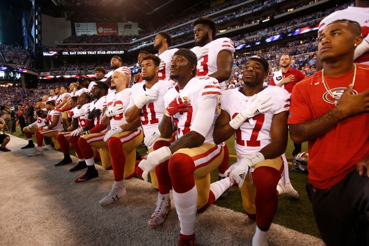 The San Francisco 49ers kneel and stand together during the anthem prior to the game against the Indianapolis Colts at Lucas Oil Stadium on October 8, 2017 in Indianapolis, Indiana.
