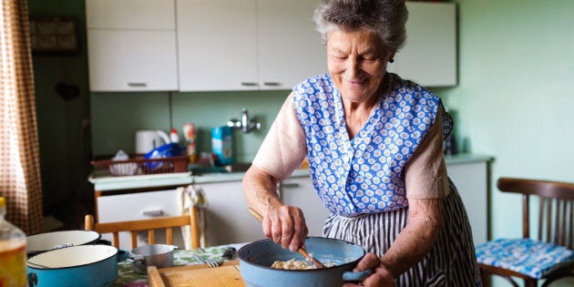 Senior woman baking pies in her home kitchen. Mixing ingredients.