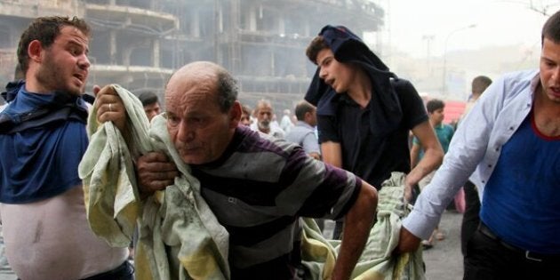 BAGHDAD, IRAQ - JULY 03: (EDITORS NOTE: Image contains graphic content.) Iraqi people carry a wounded citizen after a suicide car bombing, claimed by the terrorist organization DAESH, in the Karrada neighborhood of Baghdad, Iraq on July 03, 2016. It is reported that 60 people were killed and 100 wounded in the blast. (Photo by Amir Saadi/Anadolu Agency/Getty Images)