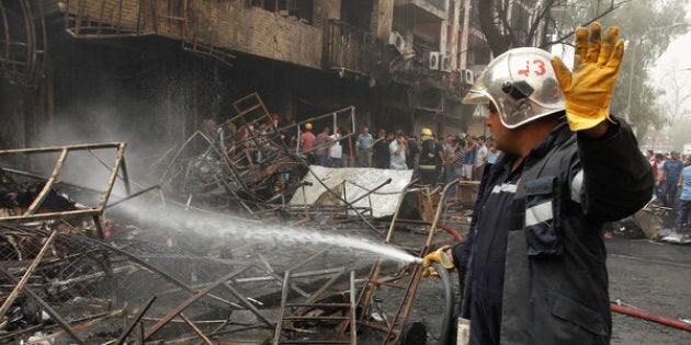 ATTENTION EDITORS - VISUAL COVERAGE OF SCENES OF INJURY OR DEATH Firemen hose down a burning building as civilians gather after a suicide car bomb occurred in the Karrada shopping area in Baghdad, Iraq July 3, 2016. REUTERS/Khalid al MousilyTEMPLATE OUT