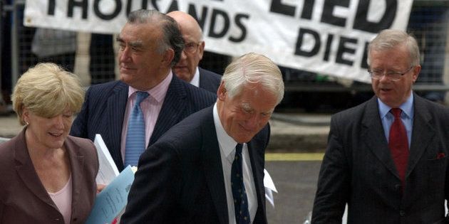 Lord Butler, centre, and his team, from left, Ann Taylor, Michael Mates, Lord Inge and Sir John Chilcott, pass protestors, as they arrive for a news conference in Westminster, London, on Thursday.