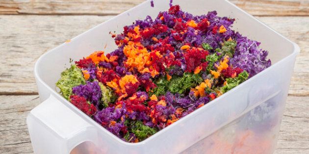 colorful juicer pulp after juicing raw vegetables (carrot, red beat, cucumber, kale, red cabbage) - a plastic cup against barn wood background