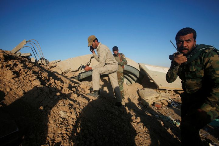 Members of the Shi'ite Badr Organisation fighters take cover behind a berm during a battle with Islamic State militants at the airport of Tal Afar west of Mosul, on November 20, 2016