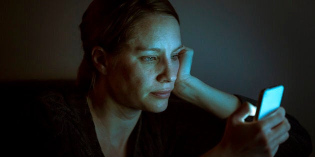 A woman illuminated by the glow of her smart phone at night