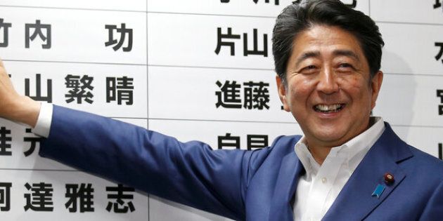 Japan's Prime Minister Shinzo Abe, leader of the ruling Liberal Democratic Party (LDP), puts a rosette on the name of a candidate who is expected to win the upper house election.
