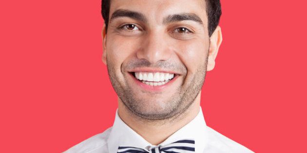 Portrait of a happy mid adult man wearing bow-tie over red background