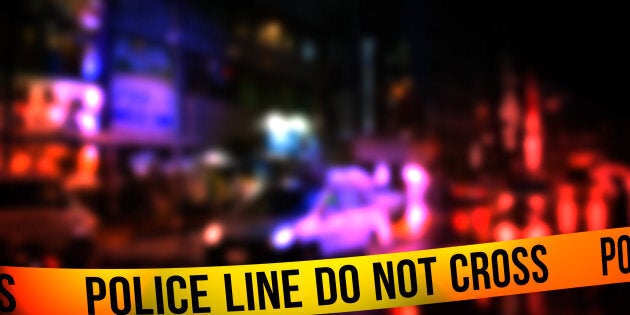 A night time street scene with focus on a 'Police Line Do Not Cross' tape