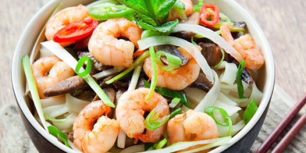 Vietnamese prawn noodle , Tasty traditional with rice noodles, spring onions, king prawns, bird's eye green, red chilies and shiitake mushrooms. Decorated with piece of fresh lime, leaves of mint, basil and slices of spicy peppers. All in bowl with chopsticks on natural wooden background.