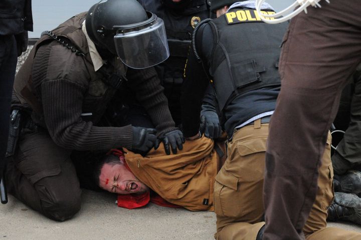 A protester is detained by police in Bismarck during a protest.