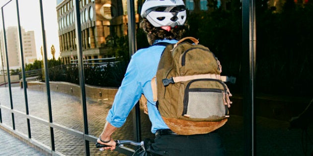 Caucasian businessman riding bicycle outside building