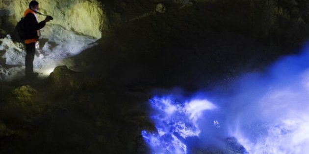 A mountain guide takes a photograph of ignited sulfuric gas, known as blue fire or blue frame, as it rises from the Ijen volcano at night in Banyuwangi, East Java, Indonesia, on Thursday, June 2, 2016. Sulfur isn't an easy material to mine manually, but the environment it's found in can be spectacular: sulfuric gases can combust on contact with air, creating an electric-blue flame. The Ijen volcano is a harsh workplace for the miners who travel there daily, as well as a tourist attraction for adventurous travelers. Photographer: Tomohiro Ohsumi/Bloomberg via Getty Images