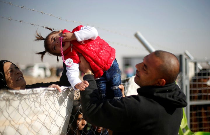 A displaced Iraqi man, who fled the Islamic State stronghold of Mosul, holds his daughter to be seen by her grandmother through a fence at Khazer camp, Iraq November 28, 2016.