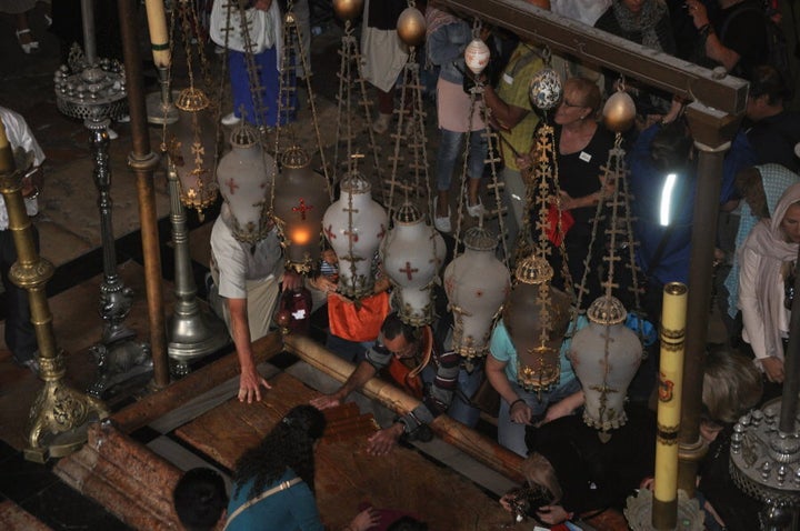 Worshippers kiss the 'anointing stone' inside the entrance of the Church. The stone is traditionally held to be the site where Jesus' body was prepared for burial.