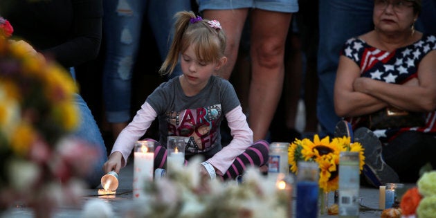 A girl lights a candle at a makeshift memorial during a vigil marking the one-week anniversary of the October 1 mass shooting in Las Vegas, Nevada U.S. October 8, 2017.