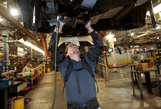 Ford Motor Co assembly worker Paul Collins wears an EksoVest as he works on the assembly line.