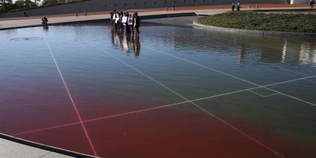 Refugee protesters stood in the fountain and spread red dye at Parliament House in Canberra