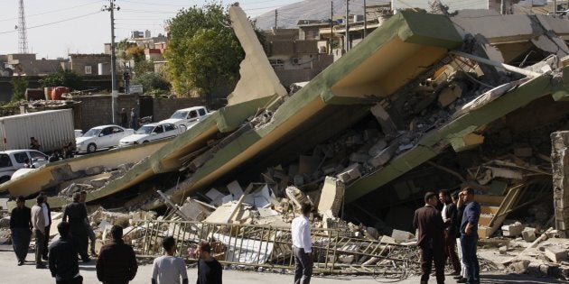 People gather around a levelled building in the mountainous town of Darbandikhan in Iraqi Kurdistan.