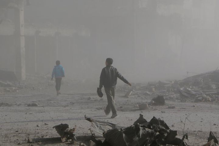 Children walk through smoke and dust after warcrafts belonging to Syrian army carried out airstrikes on the opposition controlled areas in Aleppo's Sukkeri region, Syria on December 4