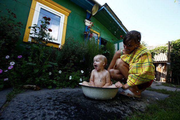 Ekaterina, a granddaughter of 75-year old Ekaterina Panchenya, bathes her daughter Dasha in a basin on a hot summer day in the village of Pogost, Belarus.