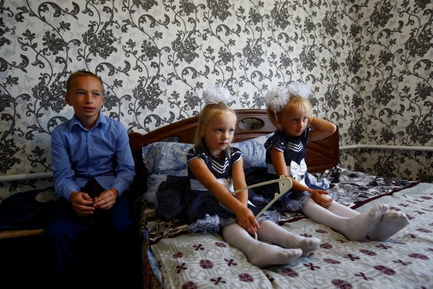 Oleg (L), Lada and Ulyana Skidan sit at their home before Oleg goes to classes on the first day of school in the village of Khrapkovo, Belarus.