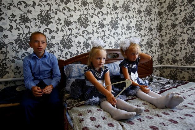 Oleg (L), Lada and Ulyana Skidan sit at their home before Oleg goes to classes on the first day of school in the village of Khrapkovo, Belarus.