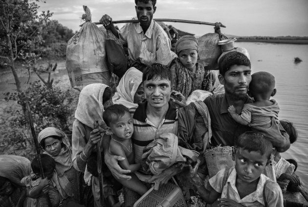 Rohingya Muslim refugees carry their belongings as they crowd on a berm while waiting to be allowed to proceed after fleeing over the border from Myanmar into Bangladesh.