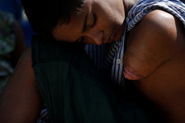 Mohamed Faisal, 13, a newly arrived Rohingya refugee who had crossed the Bangladesh-Myanmar border a few hours before, looks at what's left of his arm as he waits to get bused to a registration point at an army centre in the Teknaf area. Faisal lost his father and part of his arm when a rocket launcher hit his home at the end of August, a relative of his said.