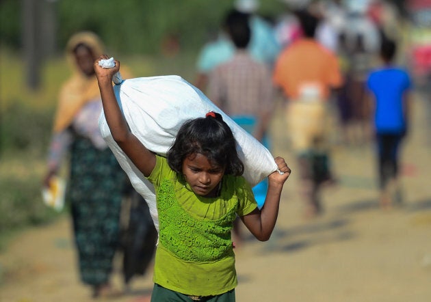 A Rohingya Muslim refugee child carries relief aid through Balukhali refugee camp in the Ukhia district of Bangladesh.