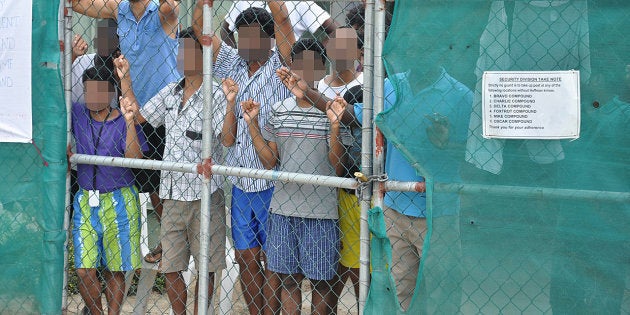 Asylum-seekers look through a fence at the Manus Island detention centre in Papua New Guinea March 21, 2014.