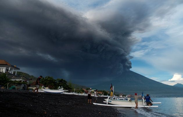 Indonesia's Mount Agung volcano erupts as fishermen pull a boat onto the beach in Amed.