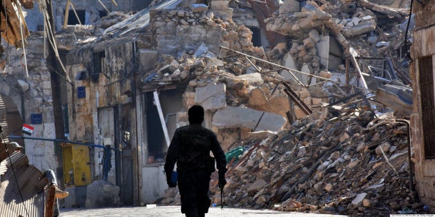 A Syrian pro-government fighter walks past damaged buildings in the Bab al-Nasr district of Aleppo's Old City on December 9, 2016.Syria's government has retaken at least 85 percent of east Aleppo, which fell to rebels in 2012, since beginning its operation on November 15. / AFP / George OURFALIAN (Photo credit should read GEORGE OURFALIAN/AFP/Getty Images)