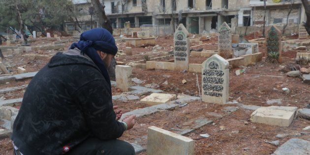 ALEPPO, SYRIA - DECEMBER 14: A man prays over the graves of family members in al-Mashhad neighborhood in Aleppo, Syria on December 14, 2016. (Photo by Ibrahim Ebu Leys/Anadolu Agency/Getty Images)