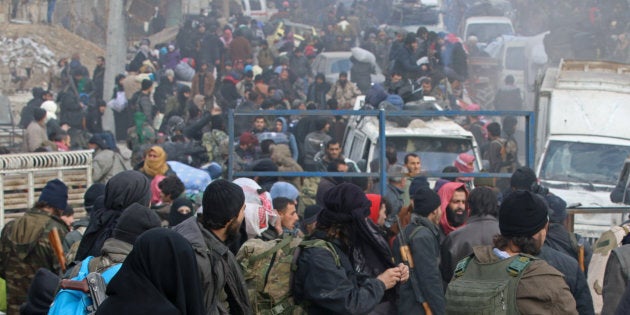 Rebel fighters sit on the rubble of damaged buildings as they wait to be evacuated from a rebel-held sector of eastern Aleppo, Syria on Dec. 16, 2016.